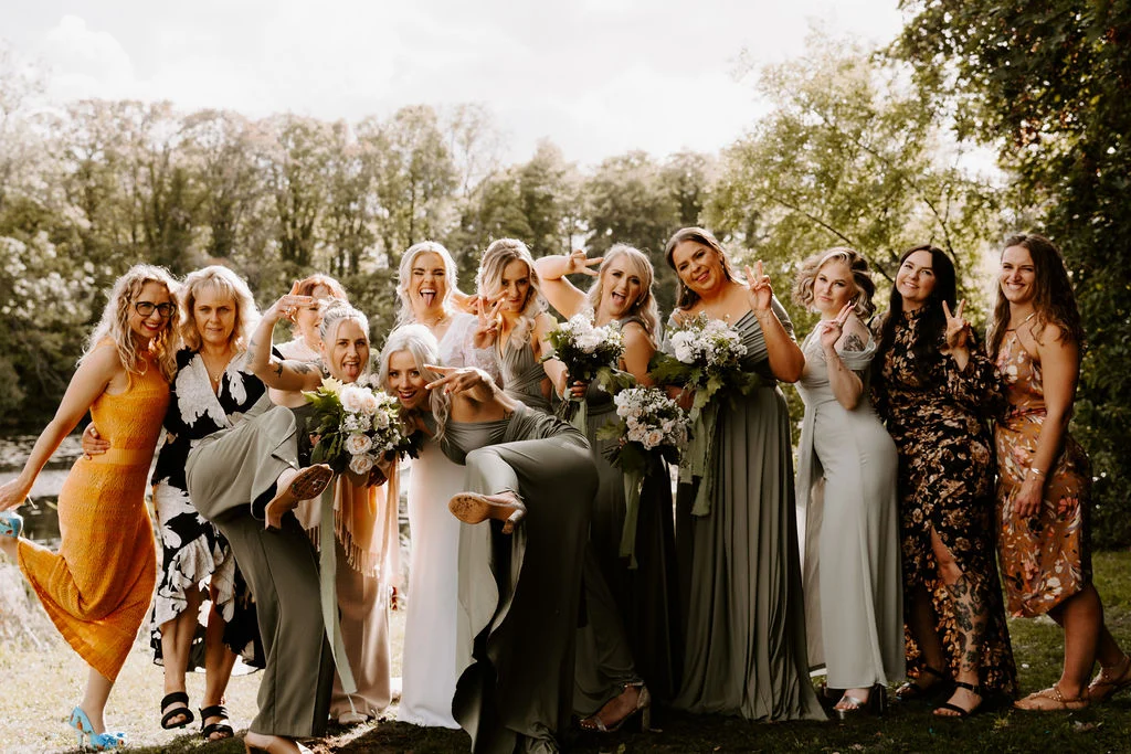 Charlotte and her wedding party raising their bouquets in the garden