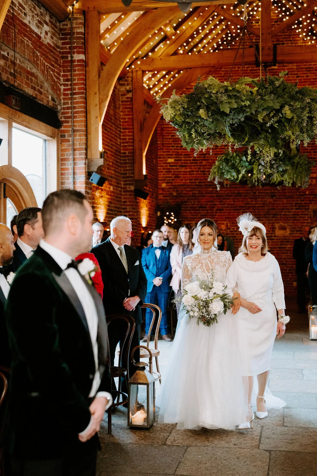 Hayley entering the timber-beamed ceremony barn with guests looking on