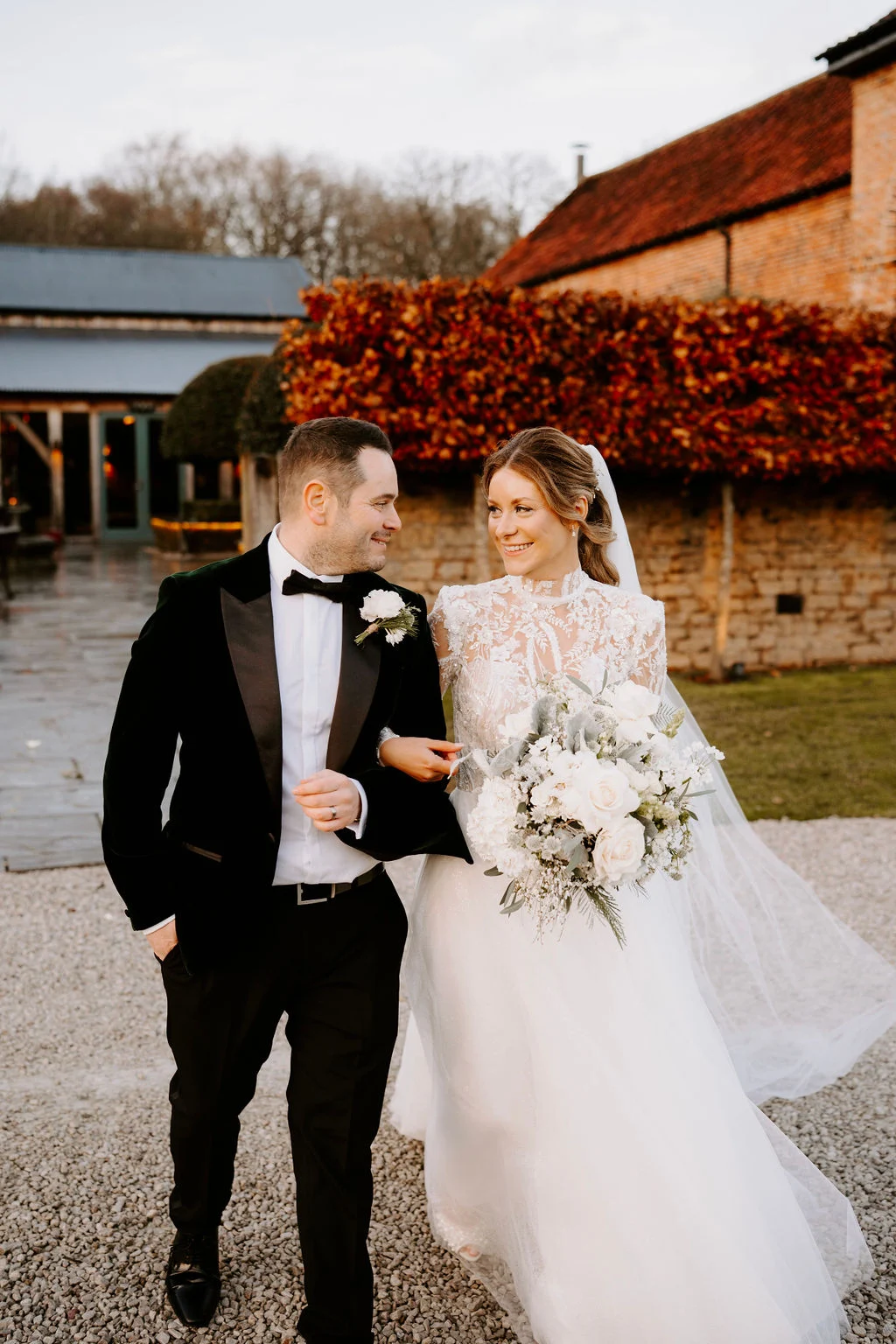 Hayley and Martin walking arm in arm beside the red-brick buildings at Hazel Gap