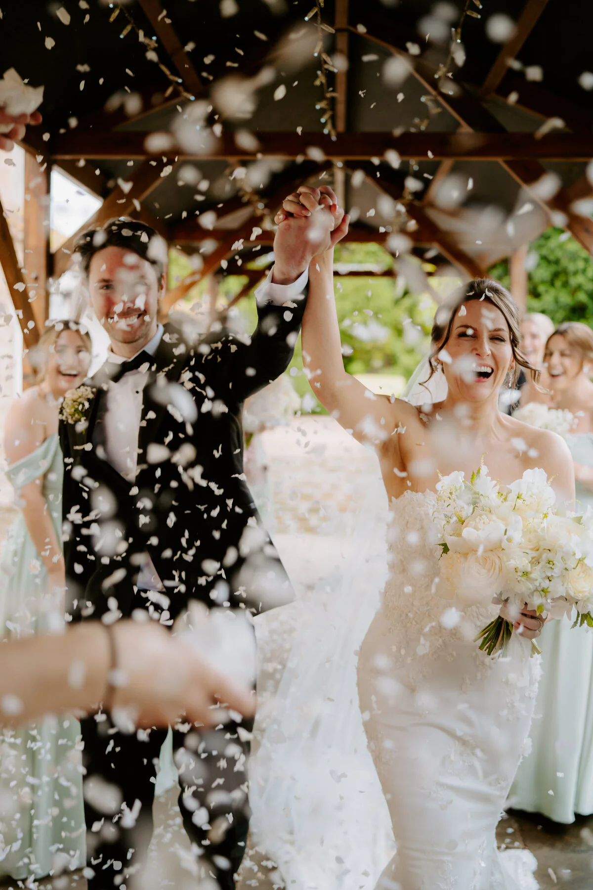 Joyful newlyweds walking through wedding confetti after their ceremony.