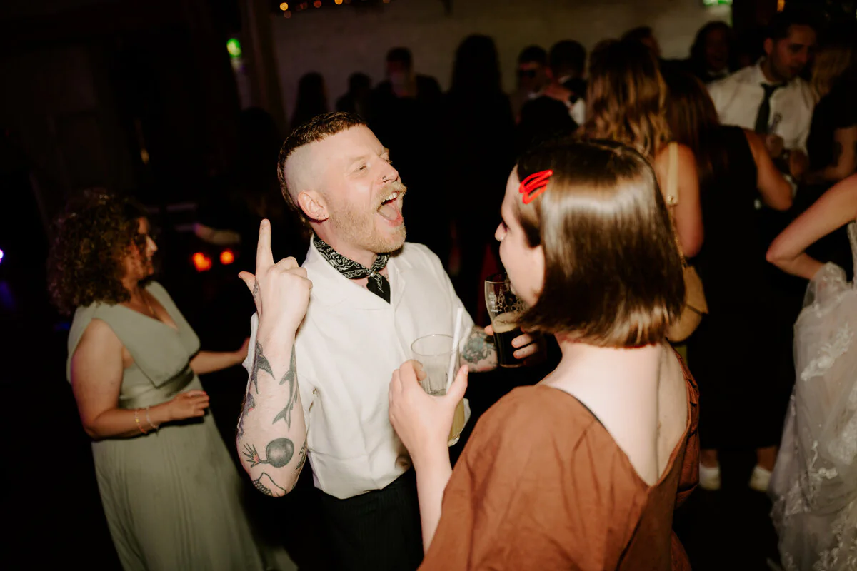 Wedding guests laughing together on the dance floor during the evening reception.