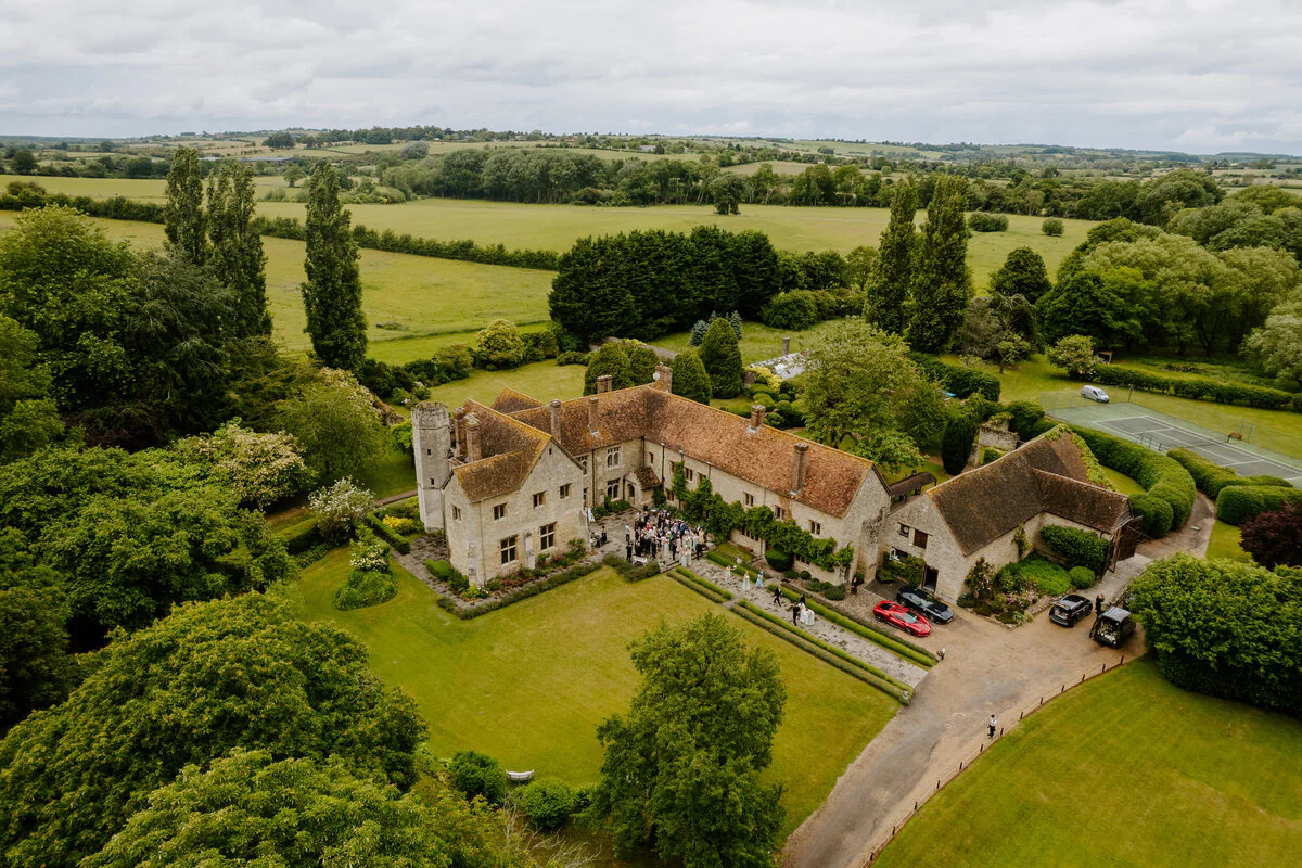 Aerial drone photograph of Charlie and Peter's stone manor house wedding venue and courtyard.