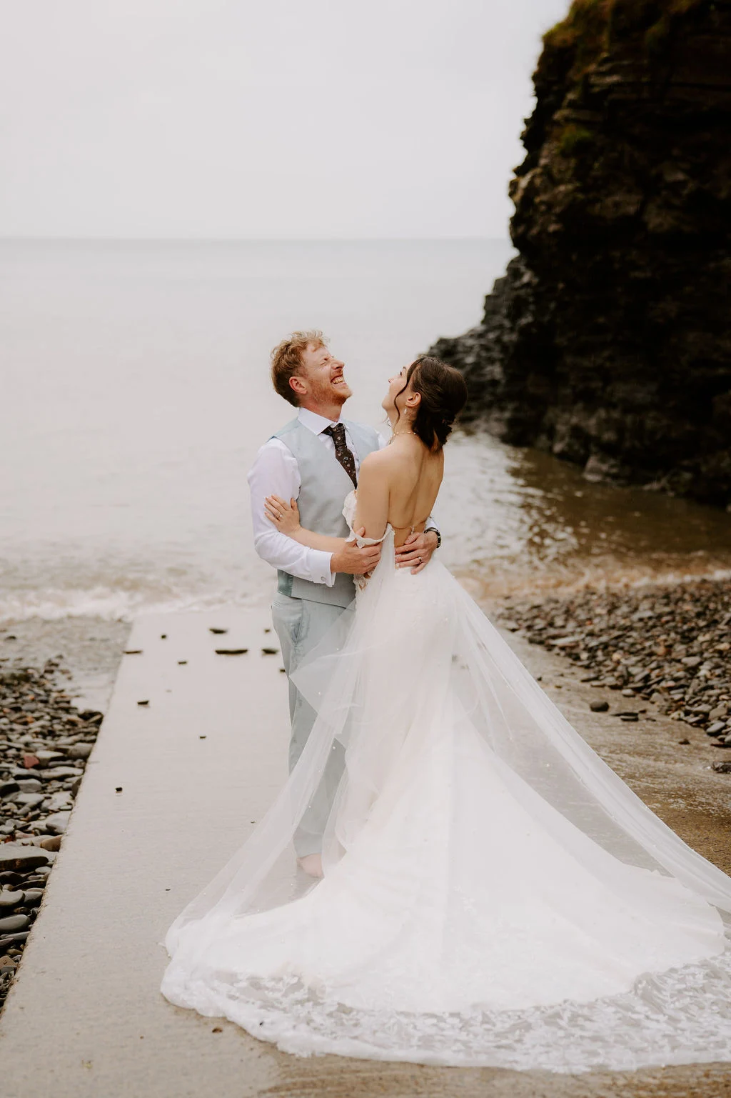 Alicia and Martin embracing together on the beach beside the cliffs