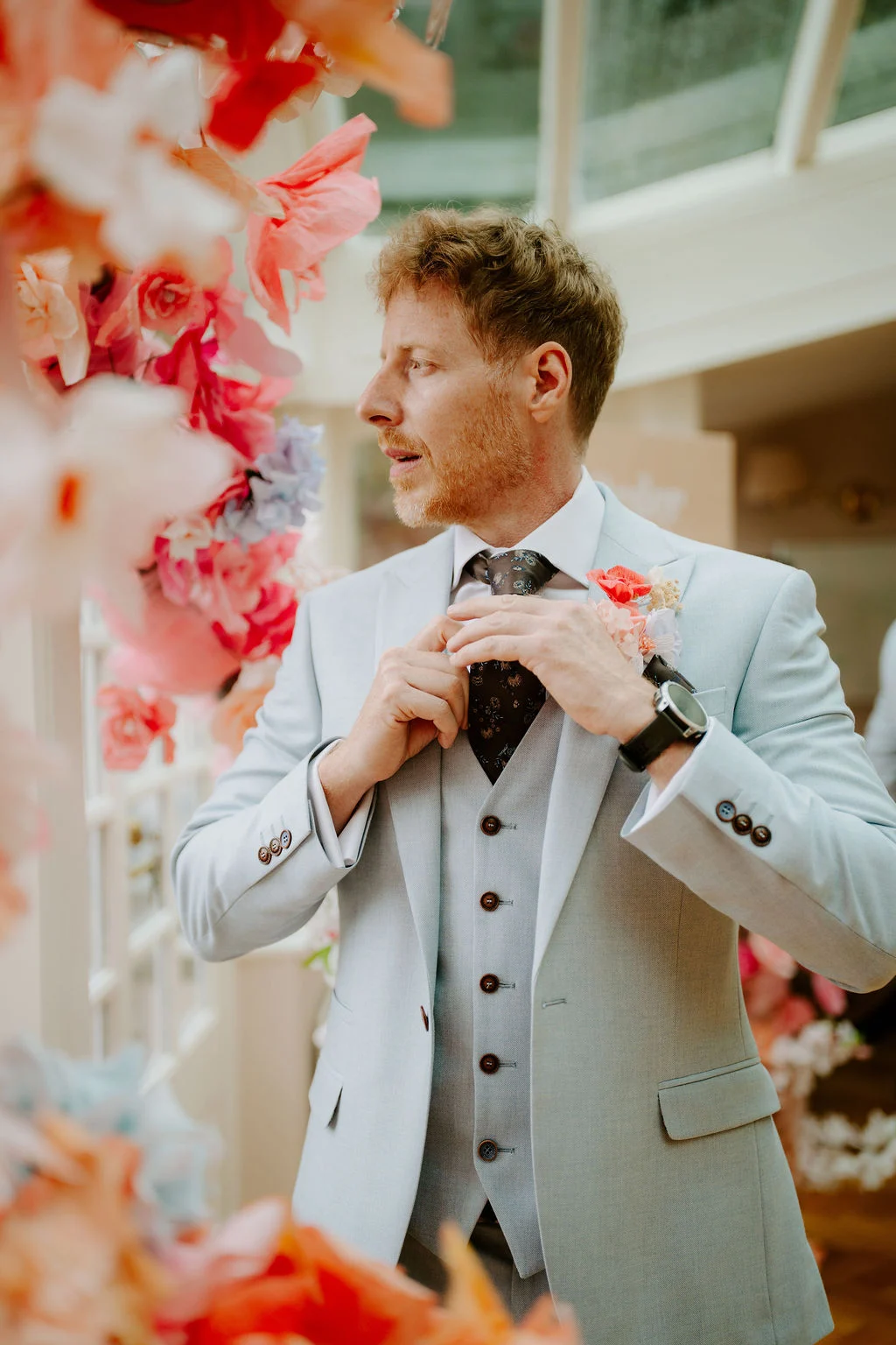 Martin adjusting his bow tie beside colourful flowers