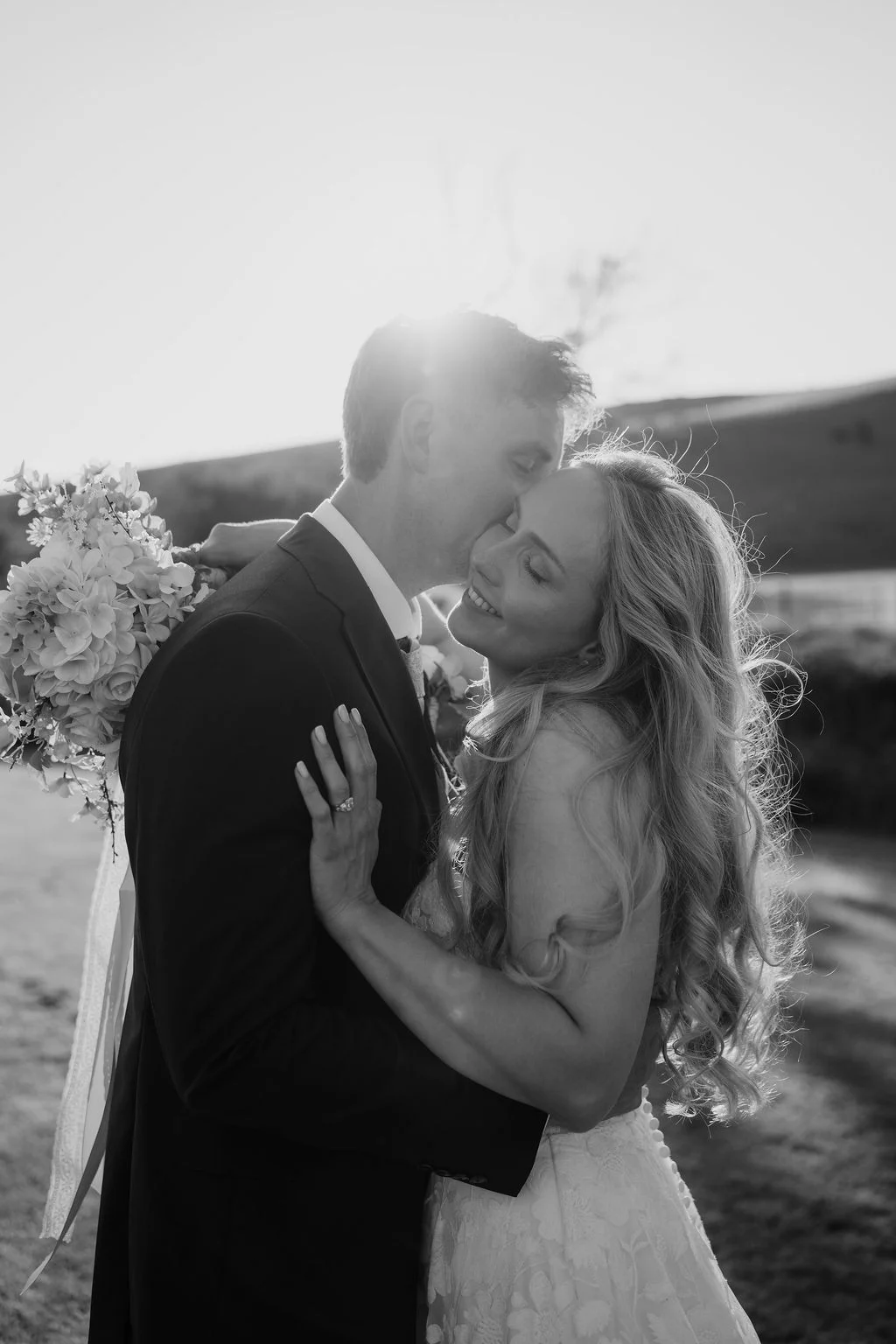 Black and white photograph of Ella and Josh kissing in the evening light