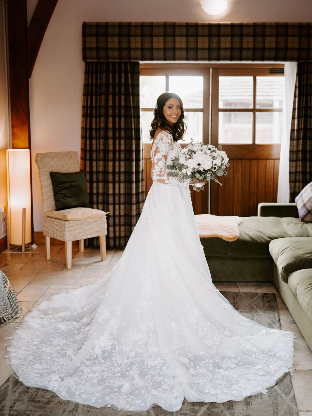 Jenny standing in her wedding dress in a room with timber furniture