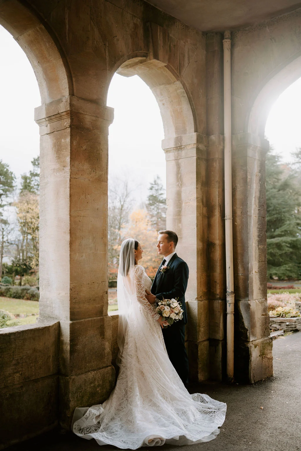 Ruth and Rhodri embracing beneath the stone arches at their ceremony location