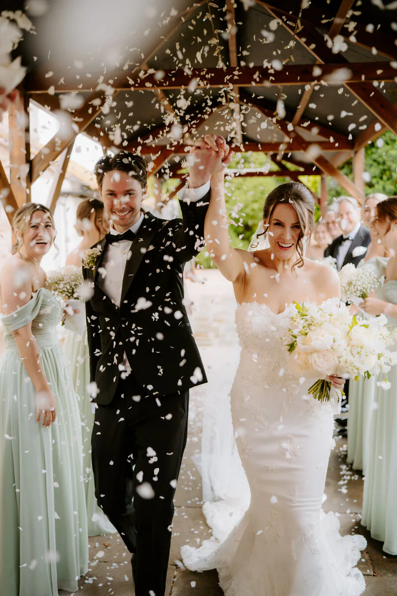A joyful newlywed couple walking through confetti