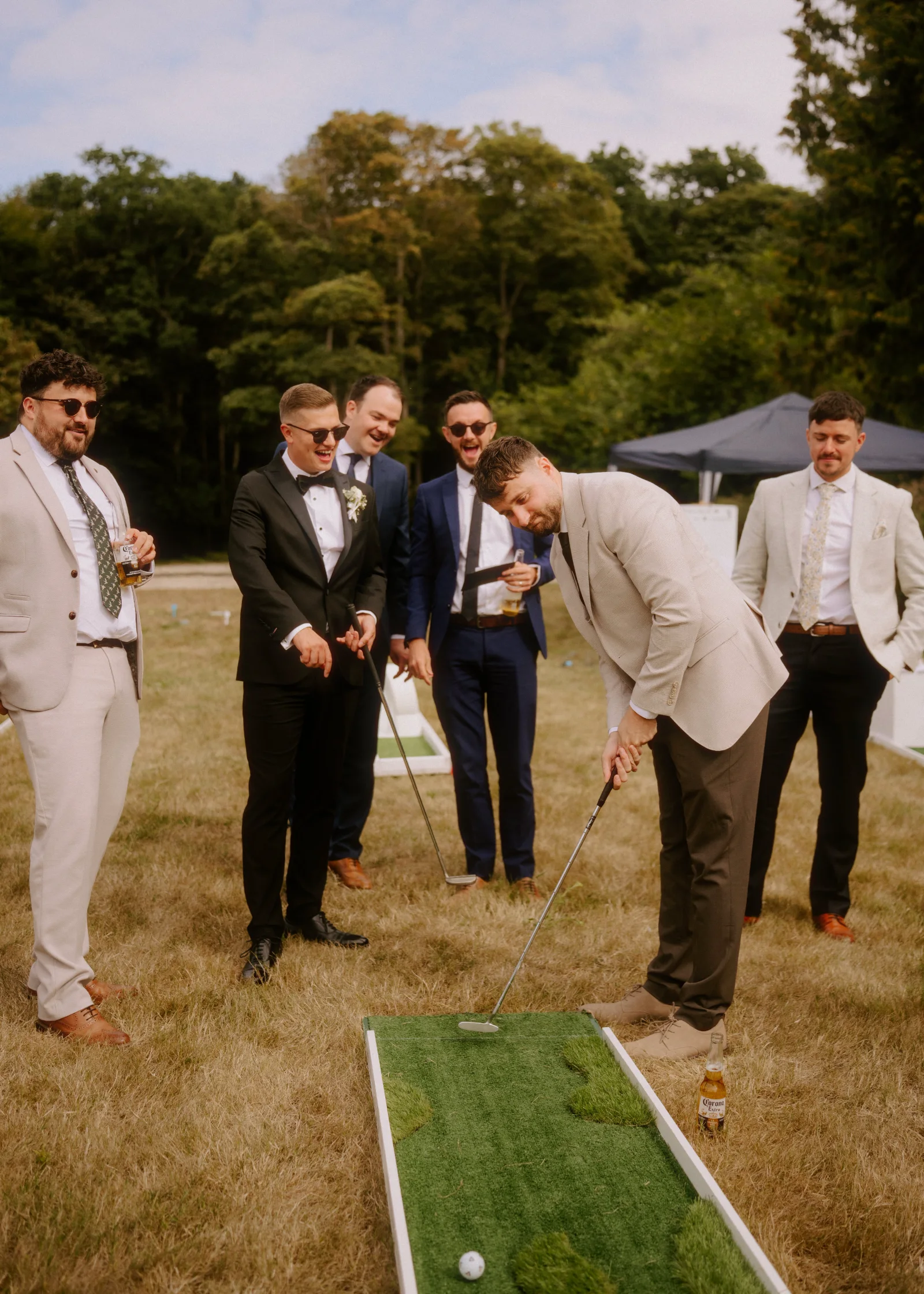 Wedding party playing lawn games on the grass outside a country house venue.