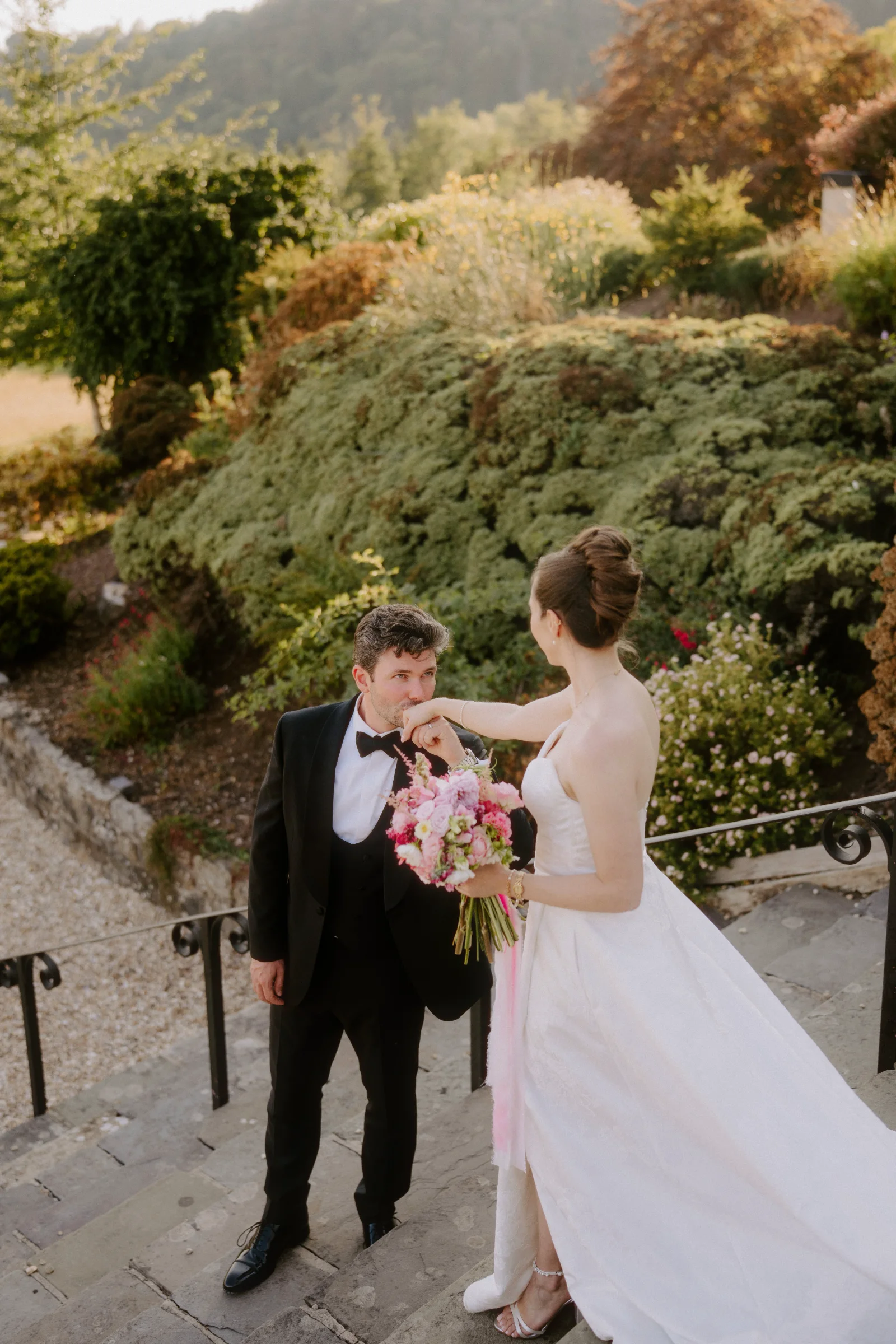 Bride and groom walking together down stone steps with a bouquet at a country house wedding.