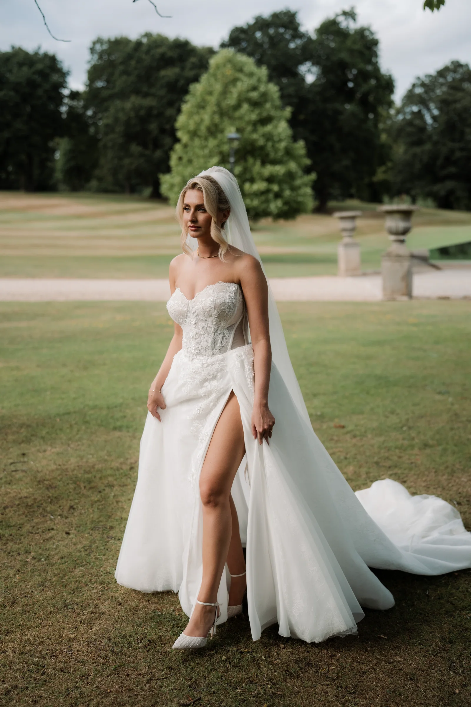 Bride in a flowing wedding dress standing on the lawn of a country house venue.