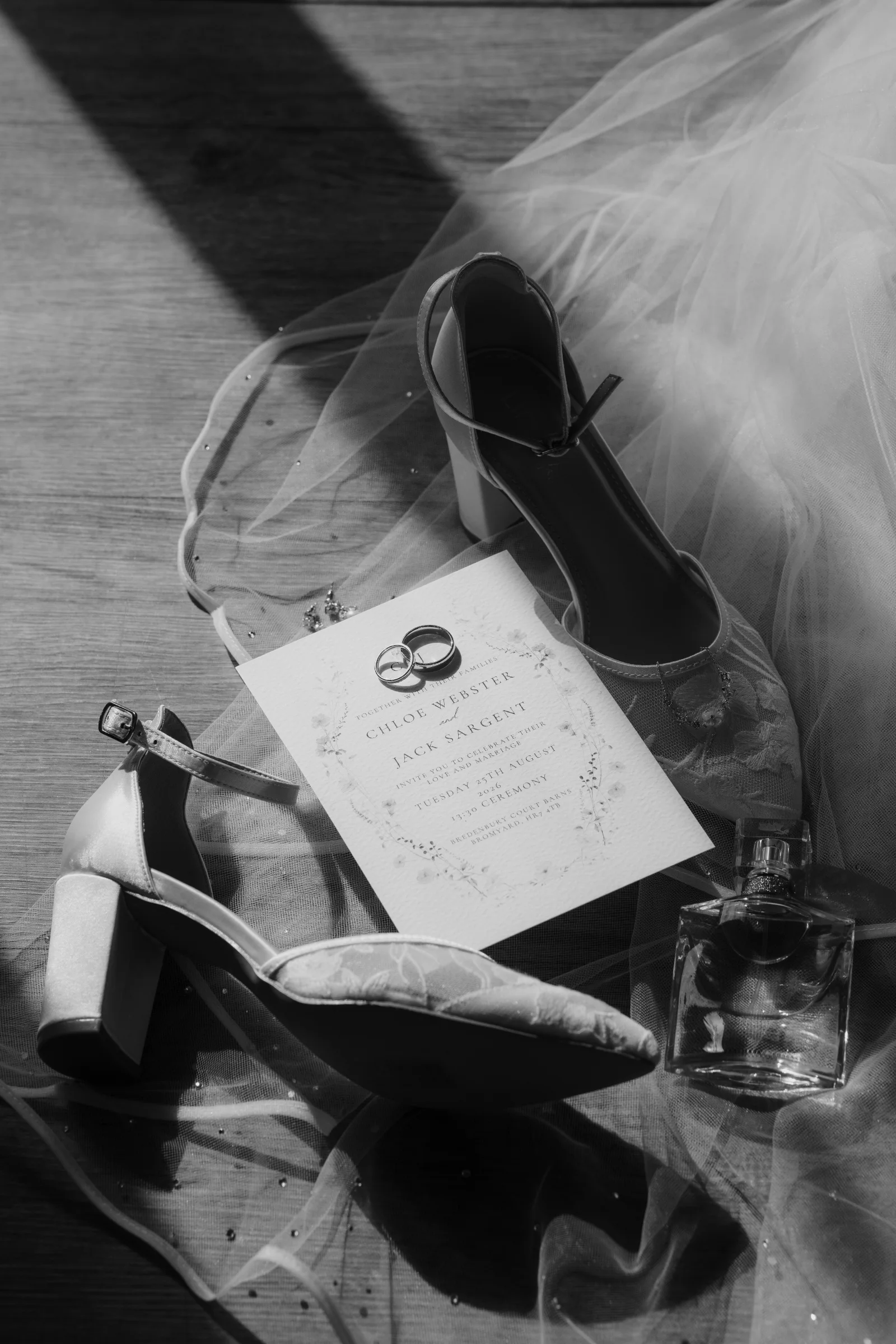Black and white wedding details showing rings, invitation, shoes and veil.