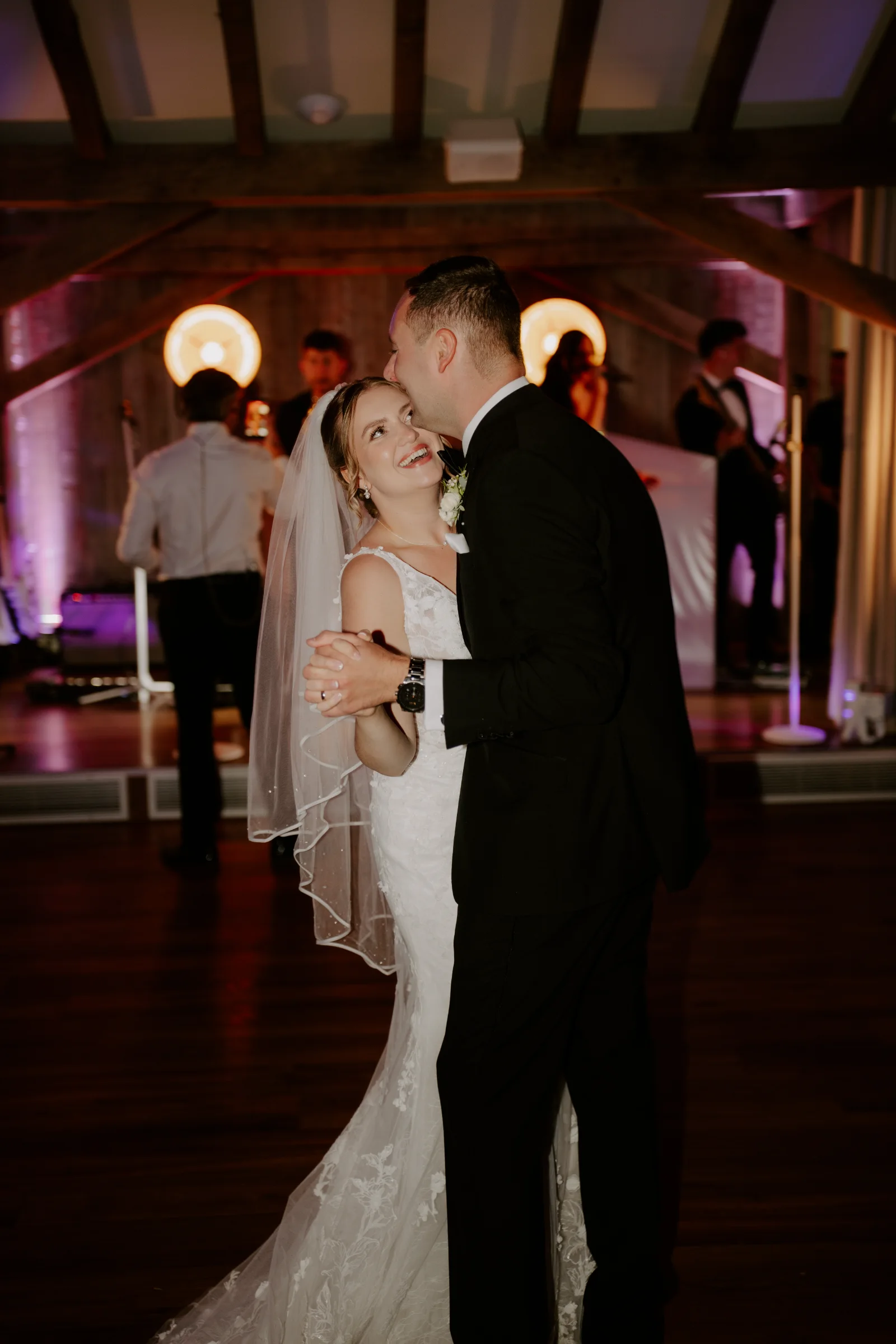 Bride and groom dancing together during their evening wedding reception.