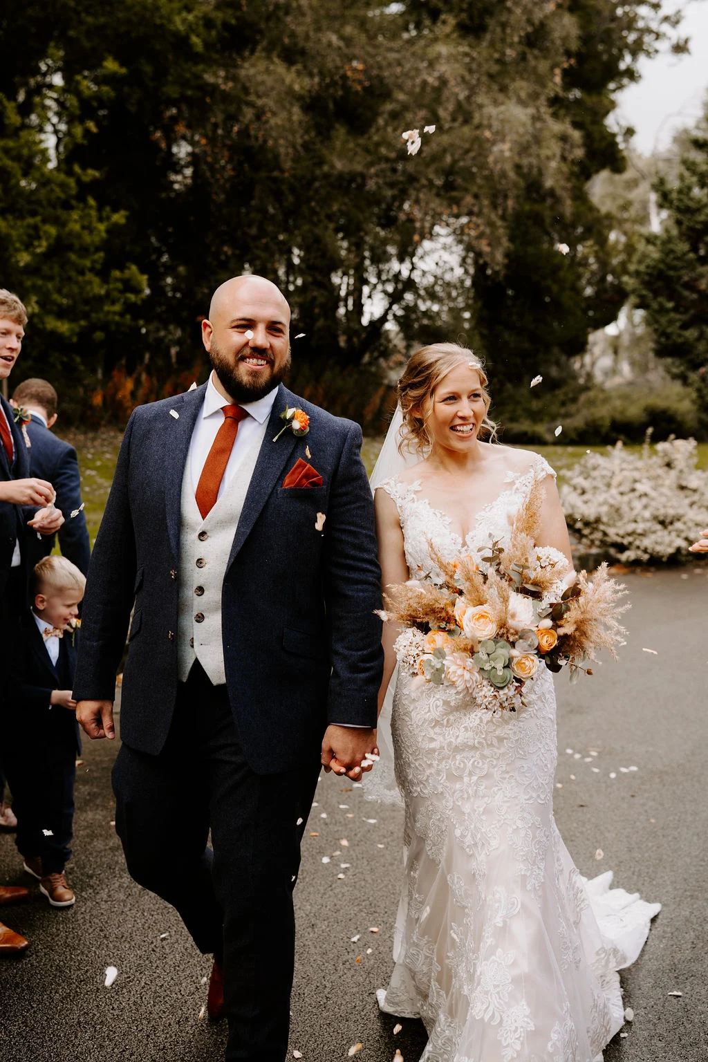 Kirsten and Ben walking hand in hand through their guests at Whirlow Brook Hall