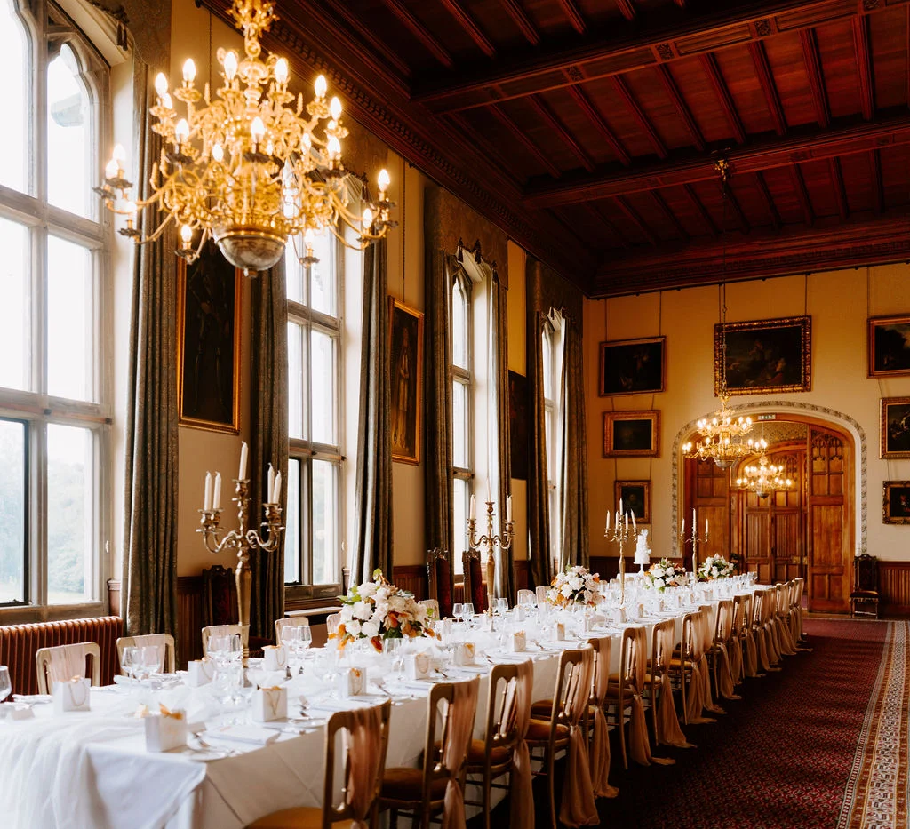 A long wedding dining table beneath chandeliers and a timber ceiling at Carlton Towers