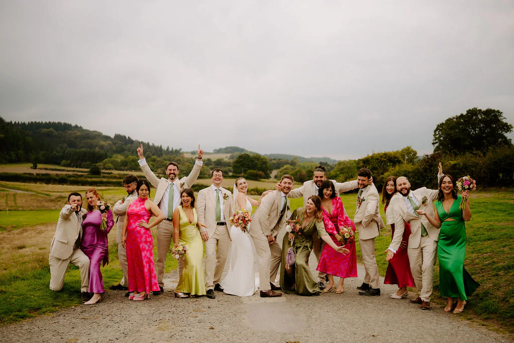 Big celebratory wedding group photo of all guests on the lawn at Wilde Lodge in the Shropshire hills