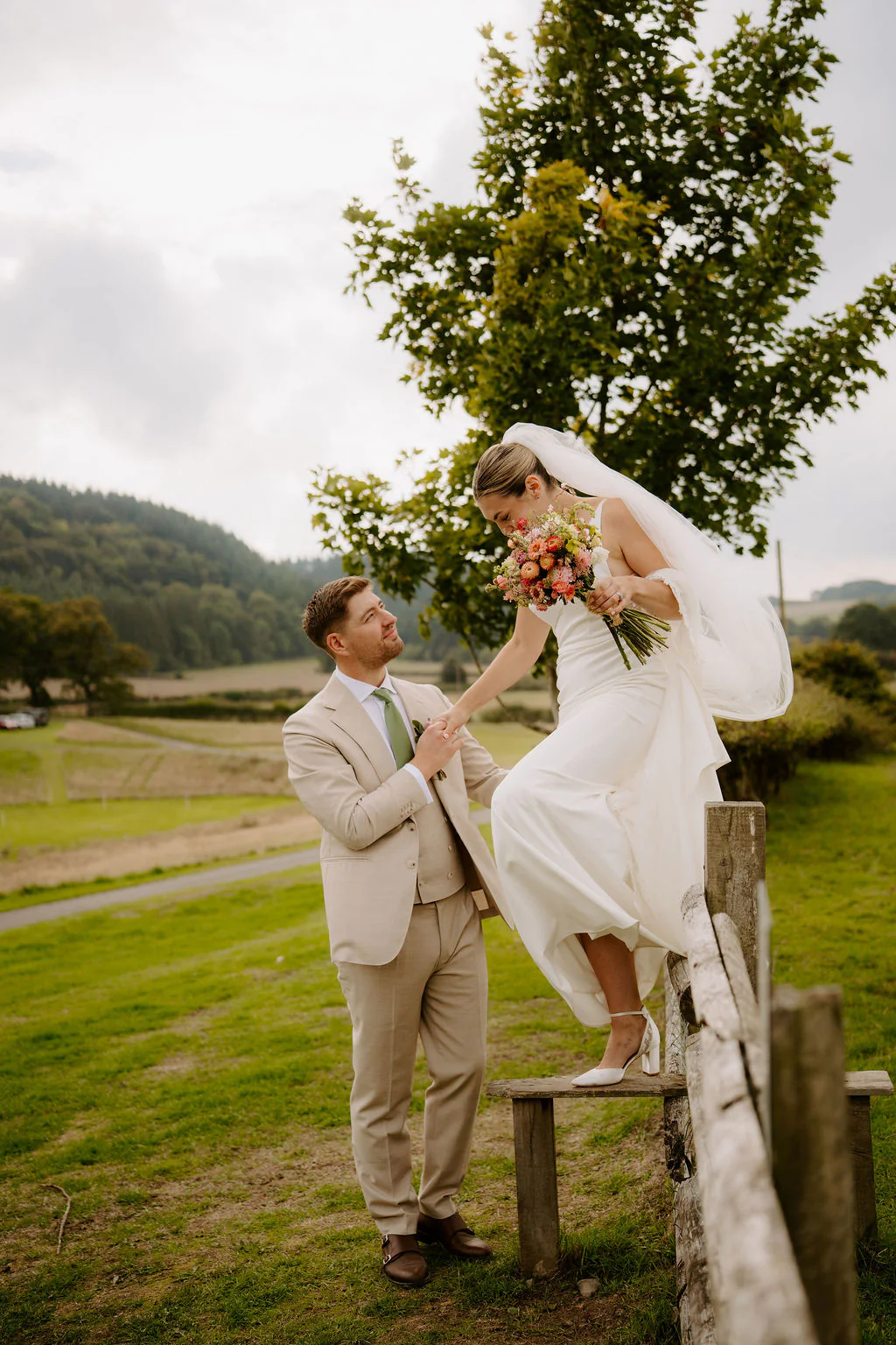 Alice & Matthew walking hand-in-hand through the wild flower meadows at Wilde Lodge