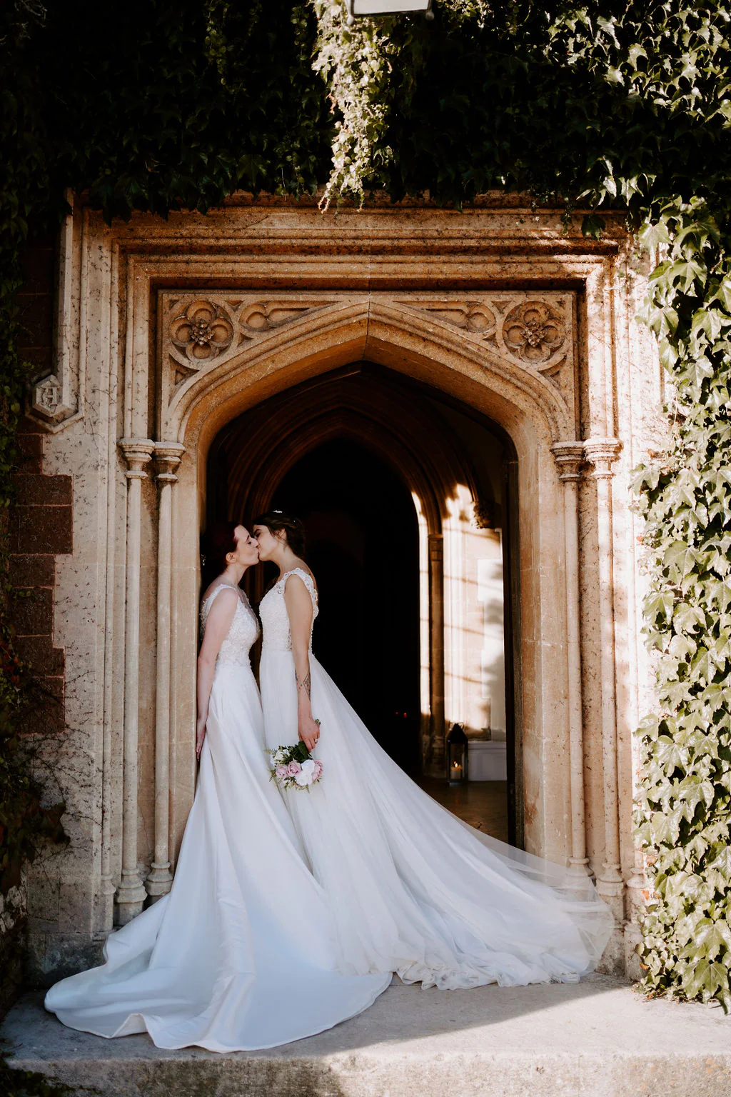 Jodie & Natalie romantic couple portrait kissing in the historic stone door arch at St Audries Park in Quantock Hills