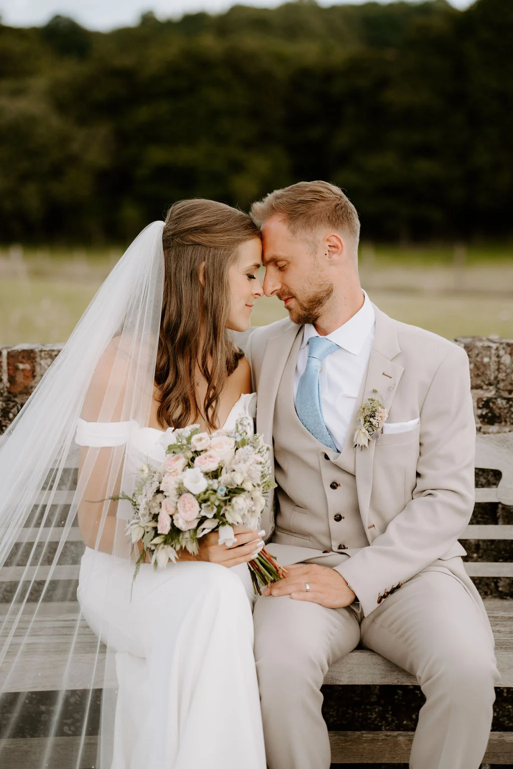Hannah and Adam kissing while seated together outdoors