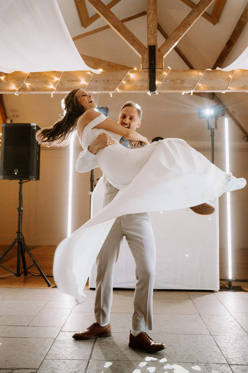 Adam lifting Hannah during their first dance beneath the barn beams