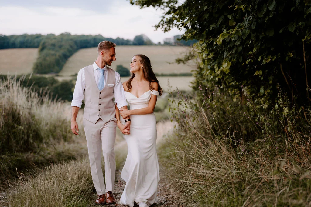 Hannah and Adam walking hand in hand along a country path