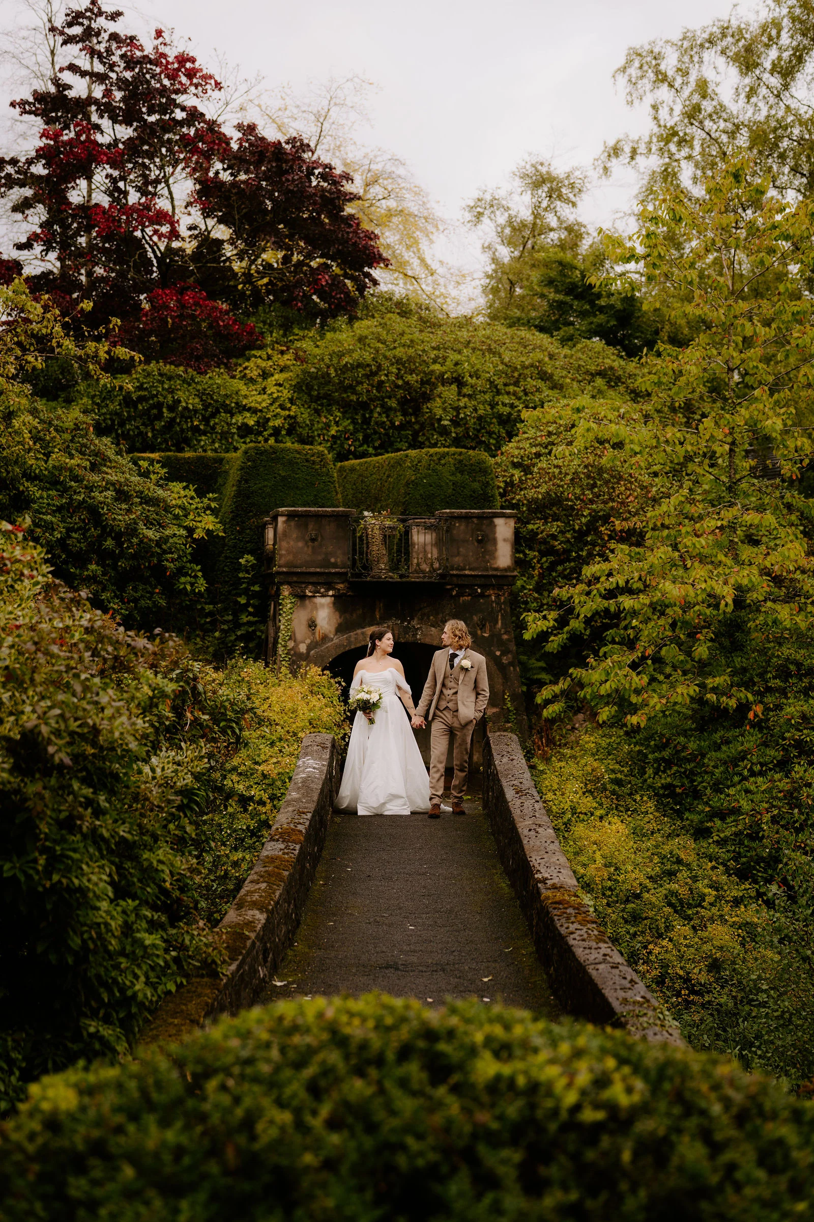 Jenny and Conan on a garden bridge surrounded by greenery at Foxtail Barns