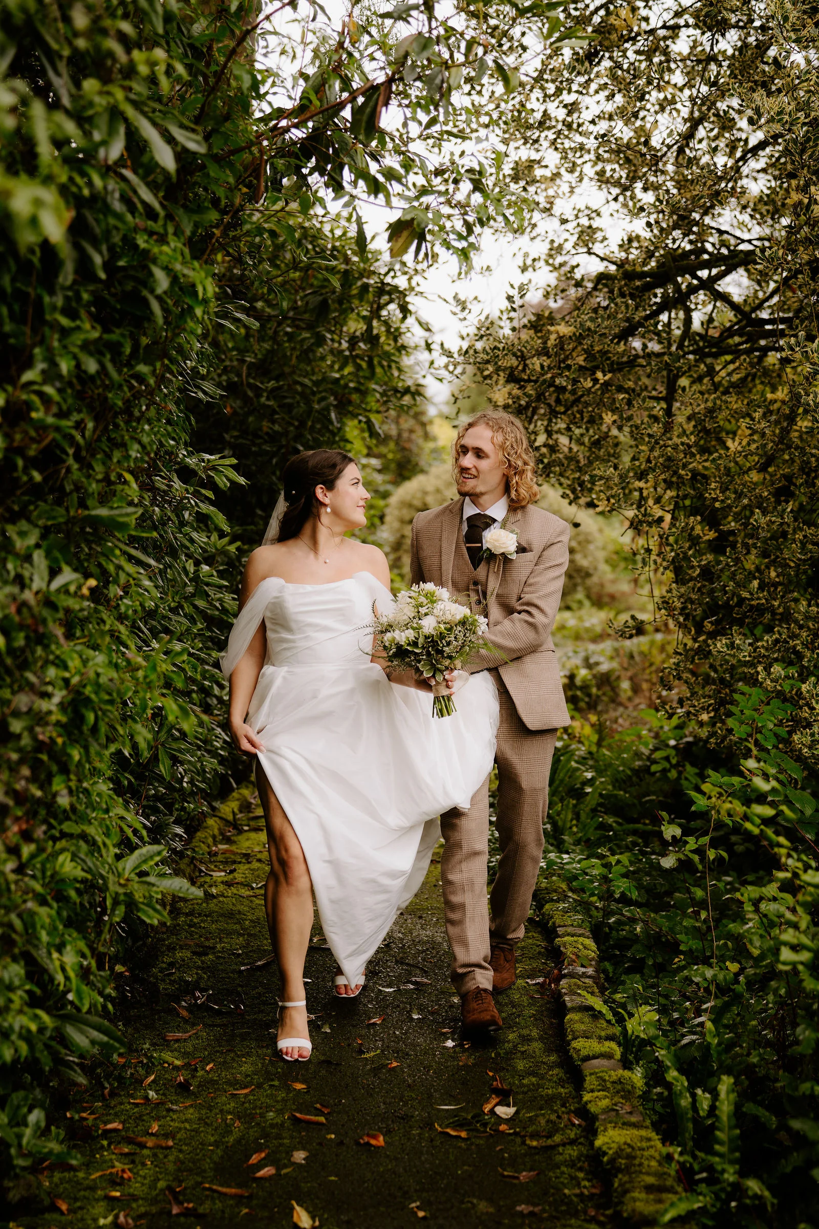 Jenny and Conan walking hand in hand along a garden path at Foxtail Barns