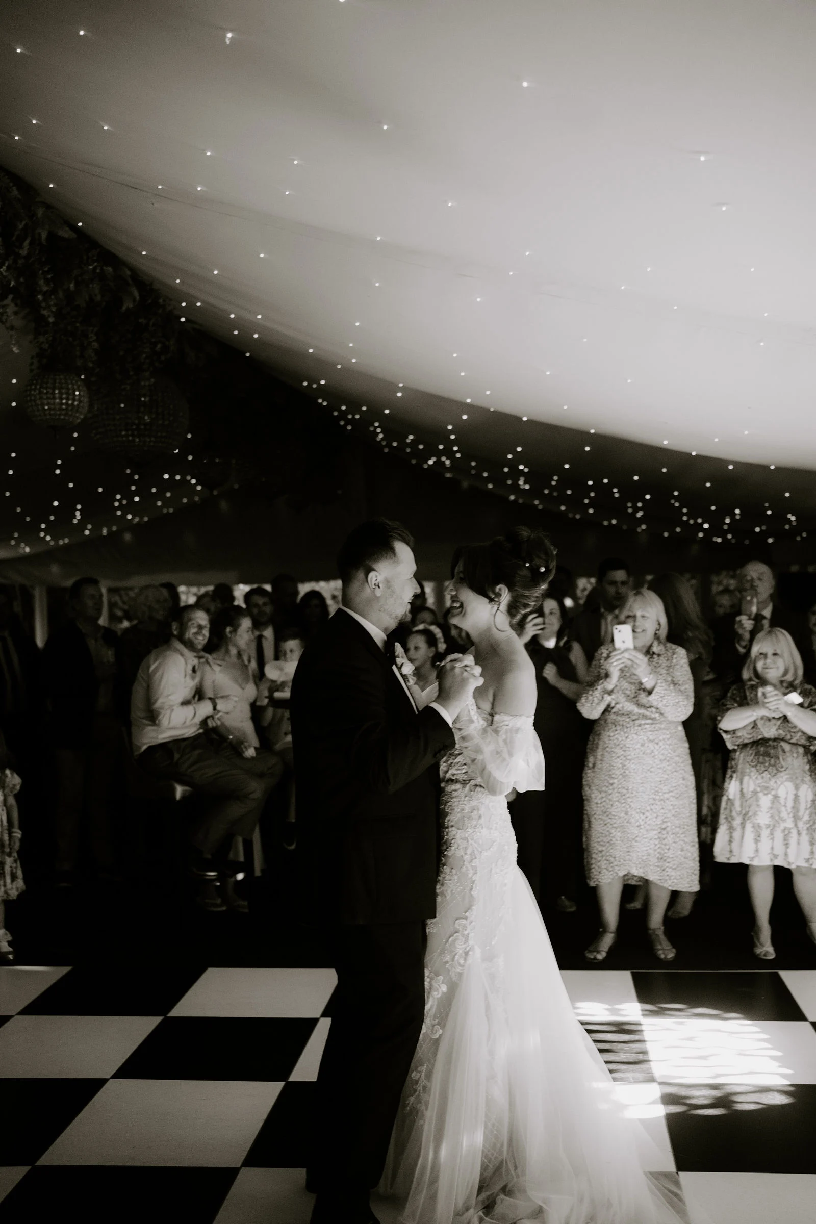 Emily and James dancing while their guests watch at Moxhull Hall in black and white