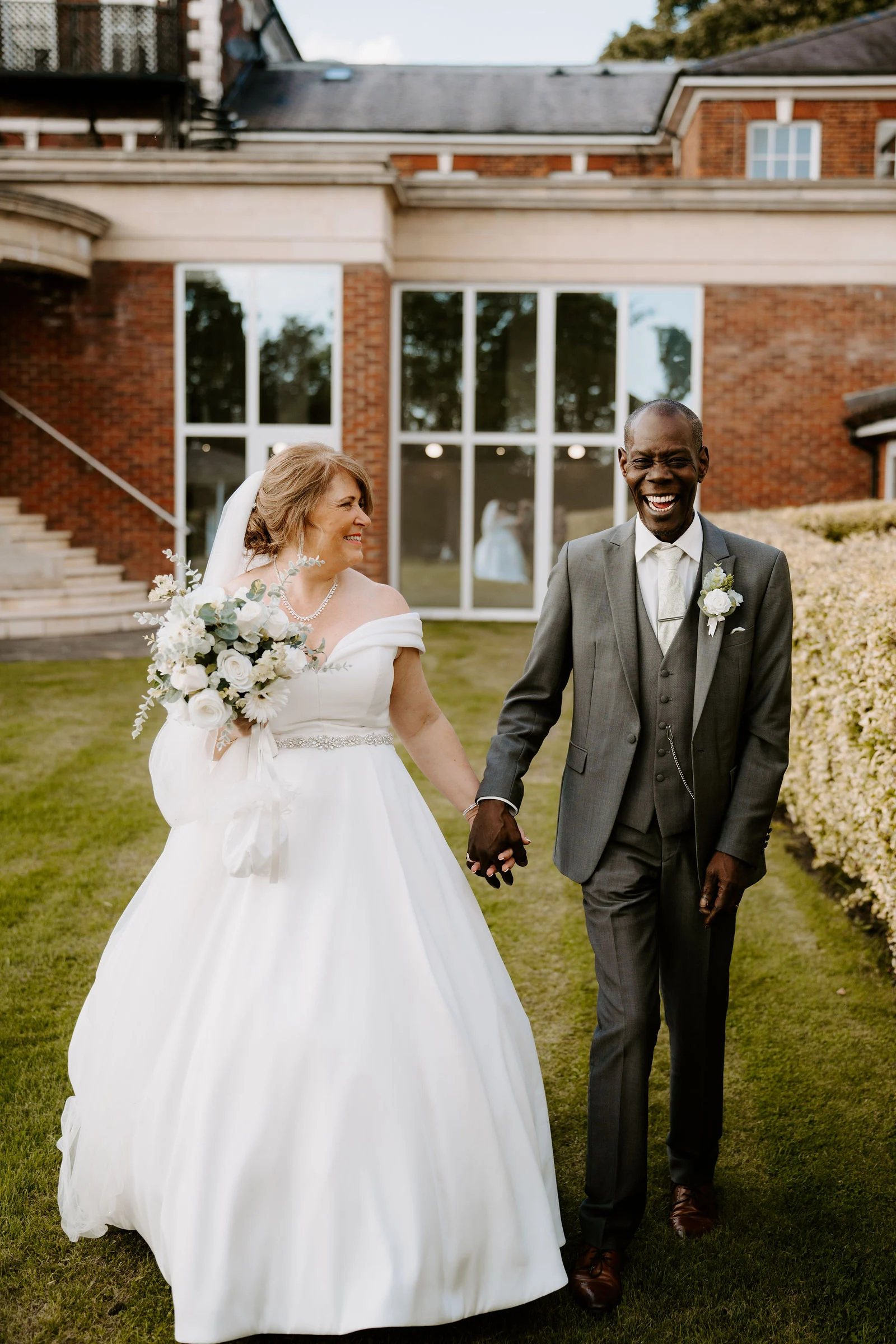 Linda and Alex walking hand in hand across the lawn at Park Hall Hotel and Spa