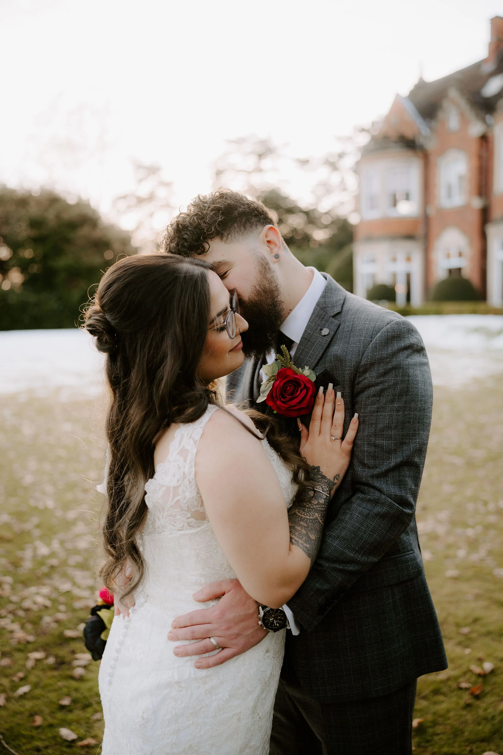 Farha and Alex embracing on the lawn with Pendrell Hall behind them