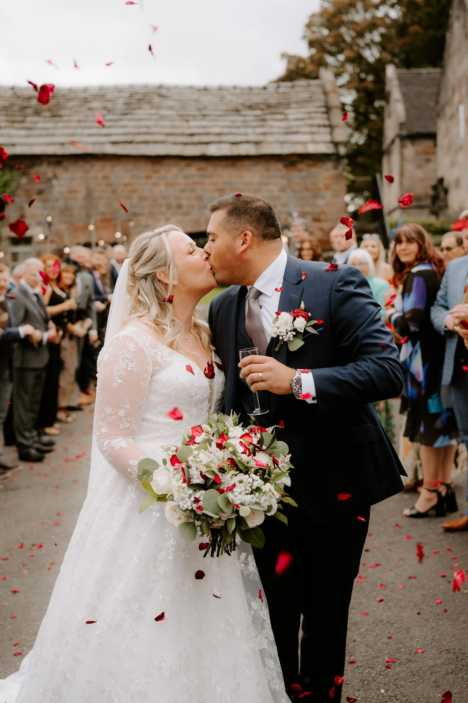 Jolene and Kelvin kissing beneath confetti outside The Ashes Barns