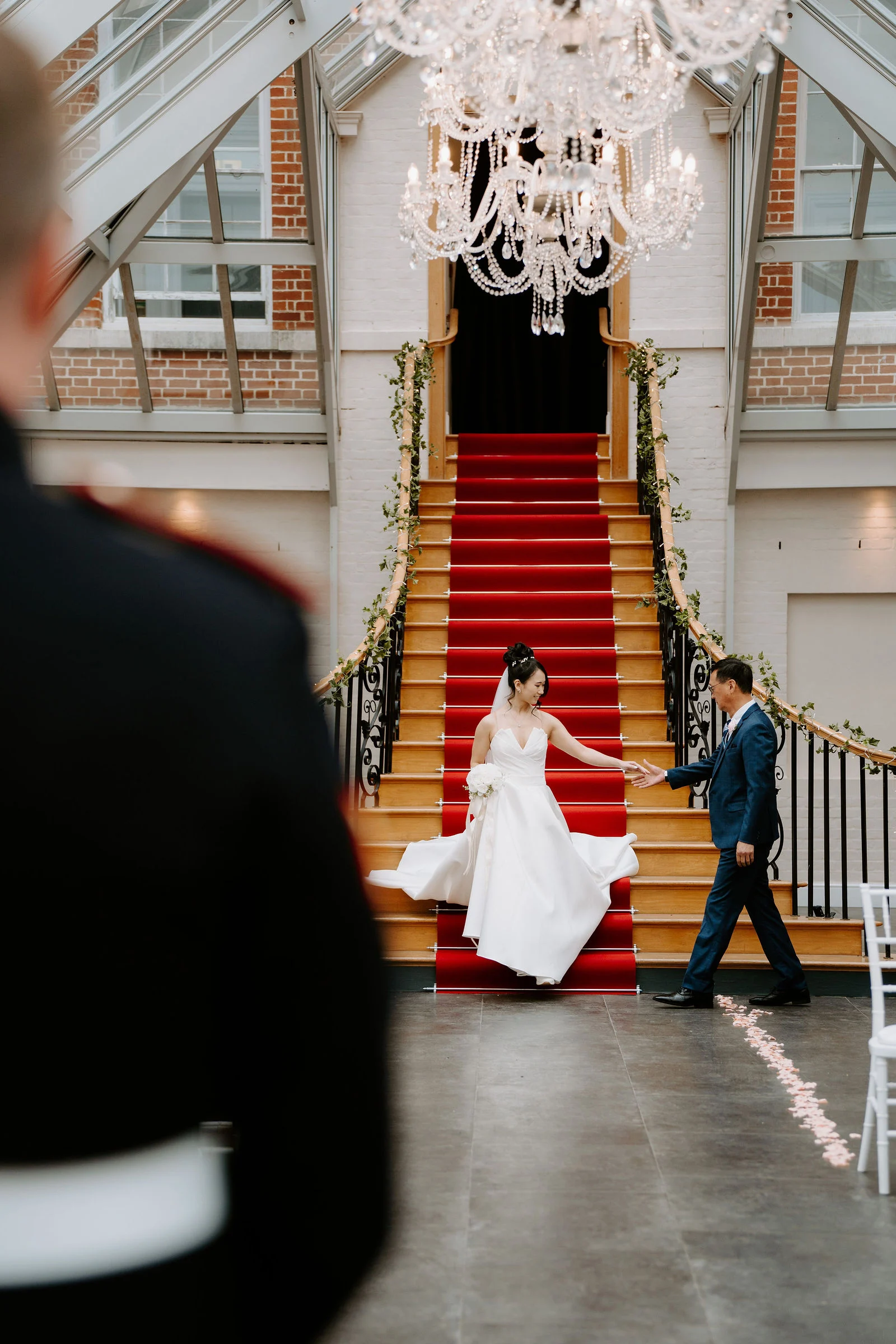 Chai and Ross standing together on the sweeping stone staircase of the Palladian mansion at Botleys Mansion in Surrey