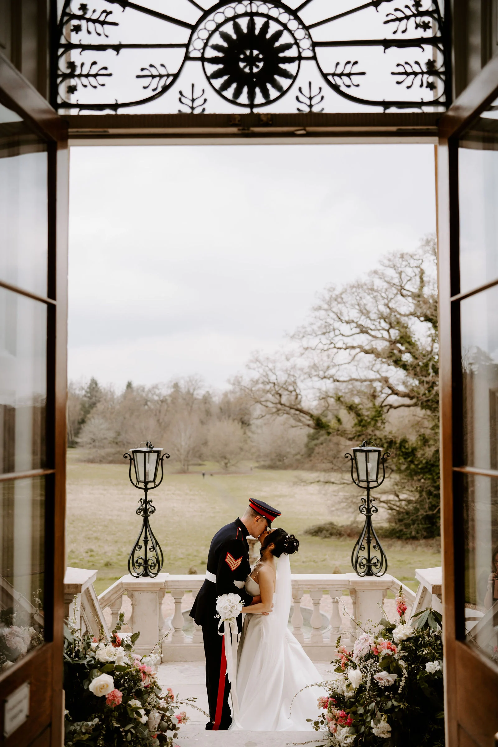 Chai and Ross walking down the aisle showered in white petal confetti inside the Botleys Mansion atrium