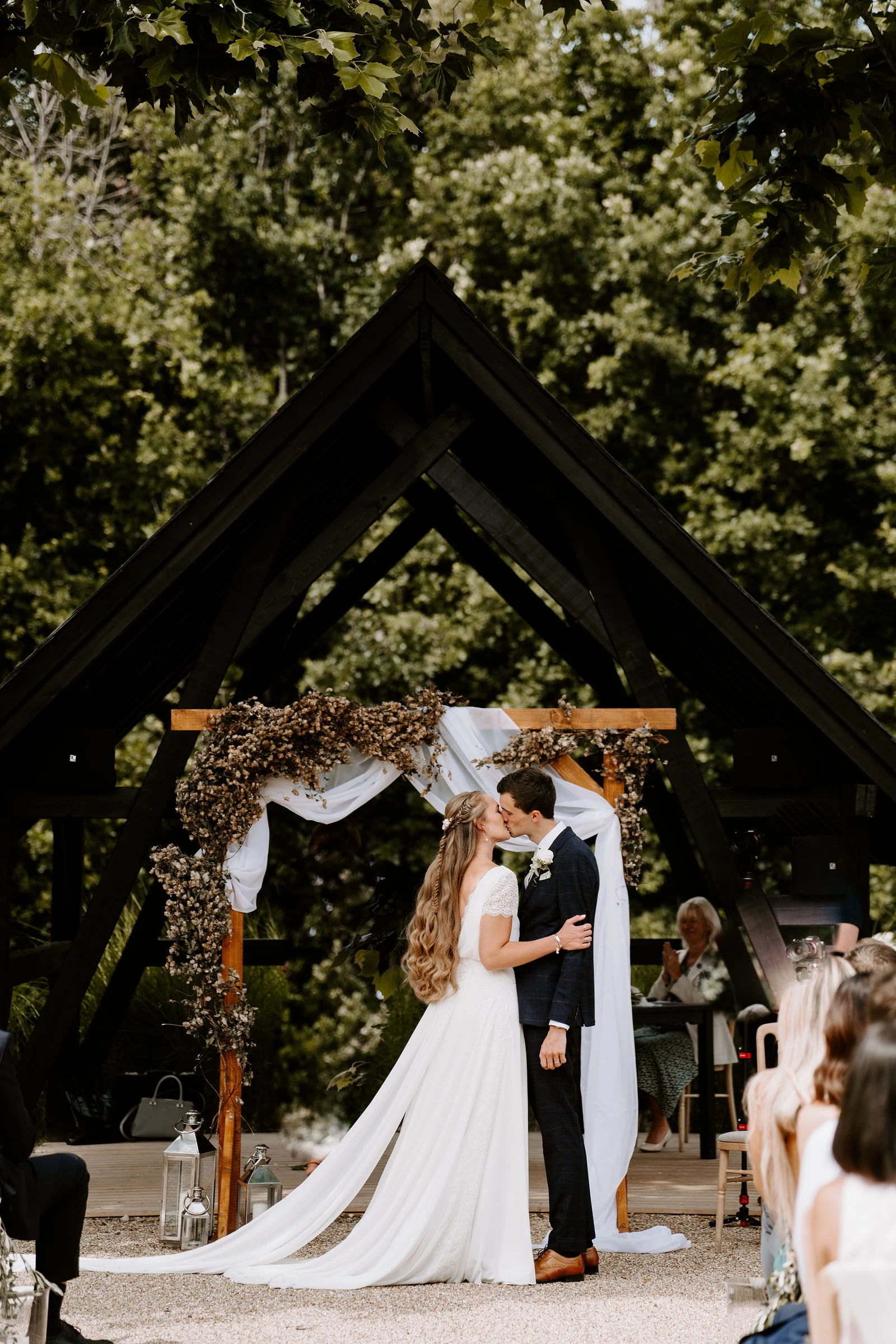 Tom and Sarah walking through a flurry of confetti in the courtyard garden at Bury Court