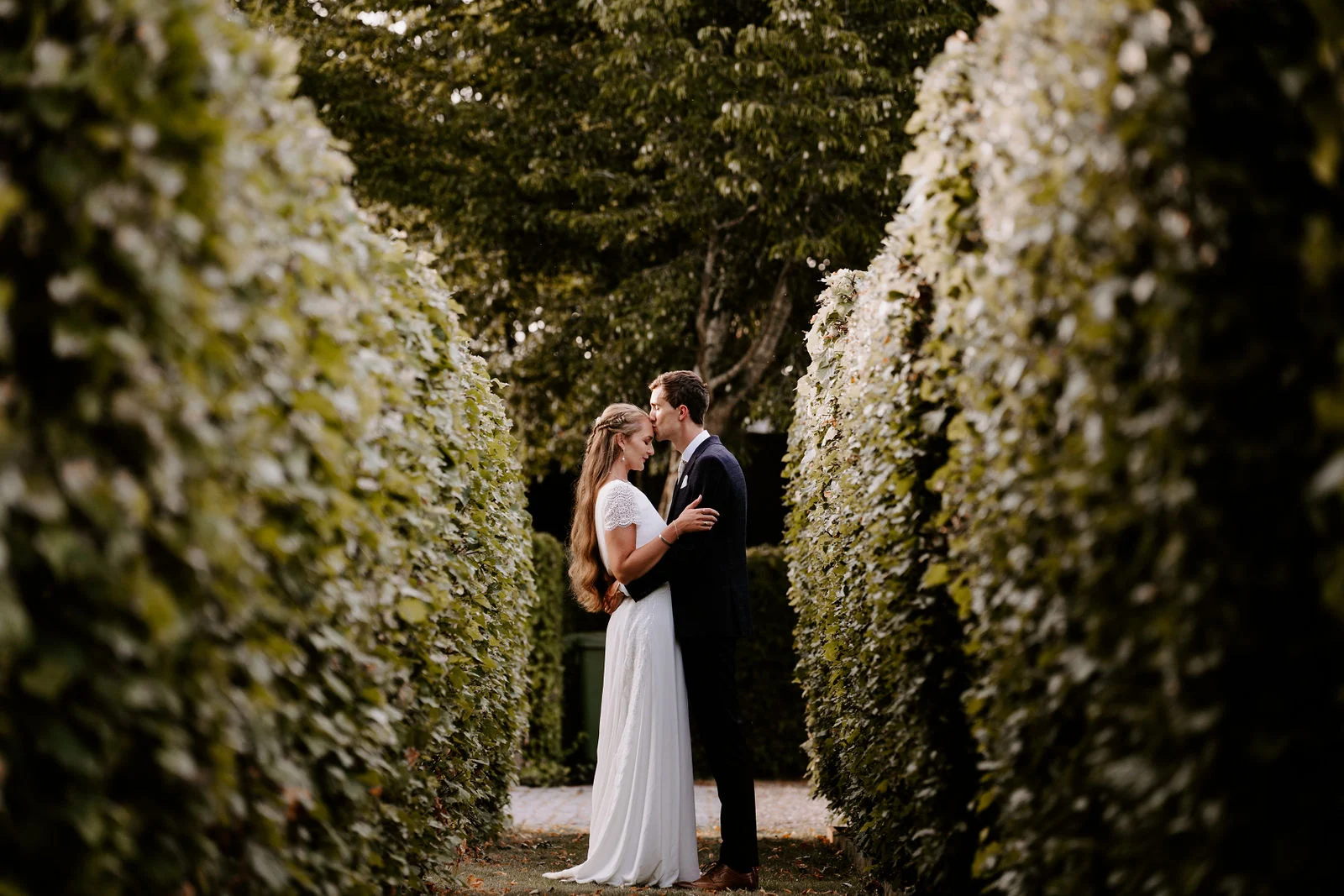 Tom and Sarah walking arm in arm across the meadow fields at Bury Court during golden hour