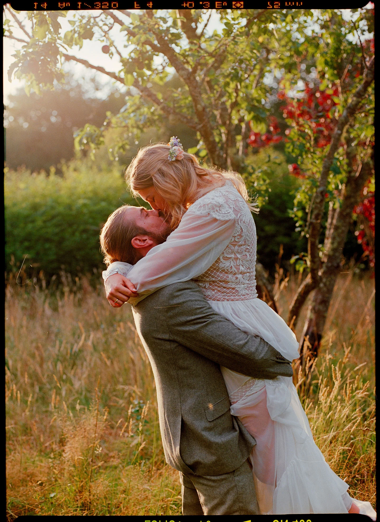 Authentic 35mm film portrait of newlyweds embraced in the Surrey Hills greenery with natural film grain and colour tonality