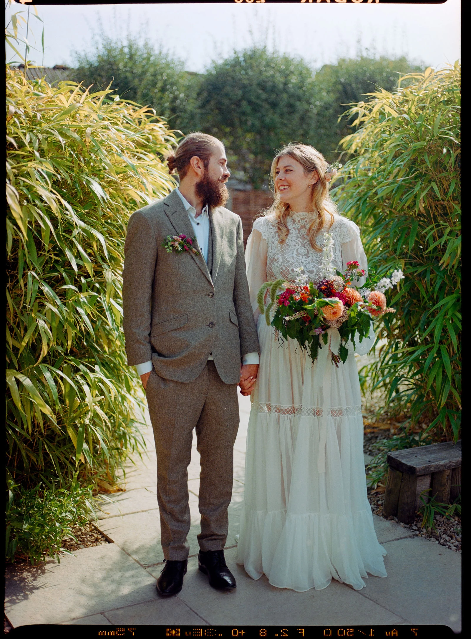 Close-up 35mm film scan of Phoebe smiling with her bridal bouquet on the farm grounds at Gate Street Barn