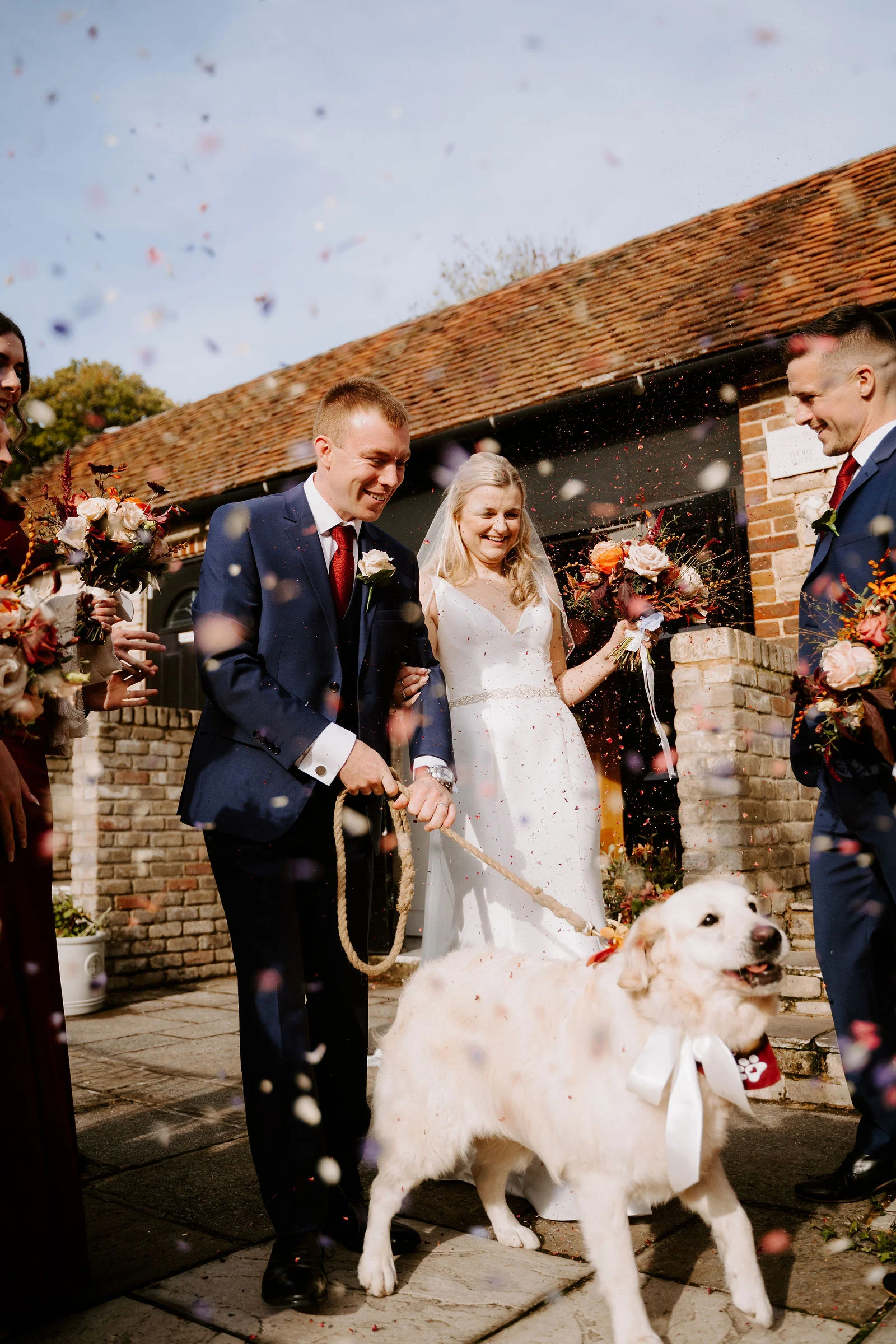 Newlyweds showered in autumn confetti as they exit through the garden doorway at Lythe Hill Hotel