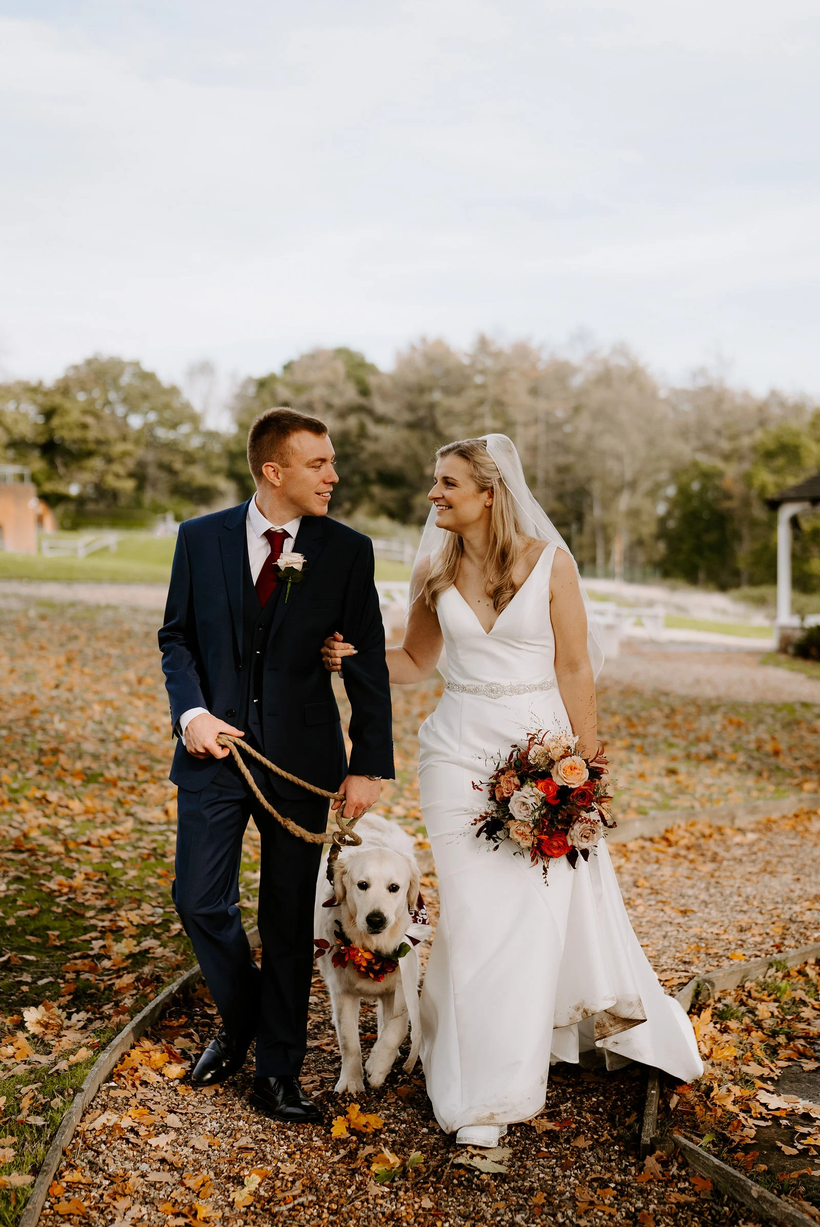 Georgie and Alastair sharing an intimate portrait embrace beneath autumn trees on the Lythe Hill estate
