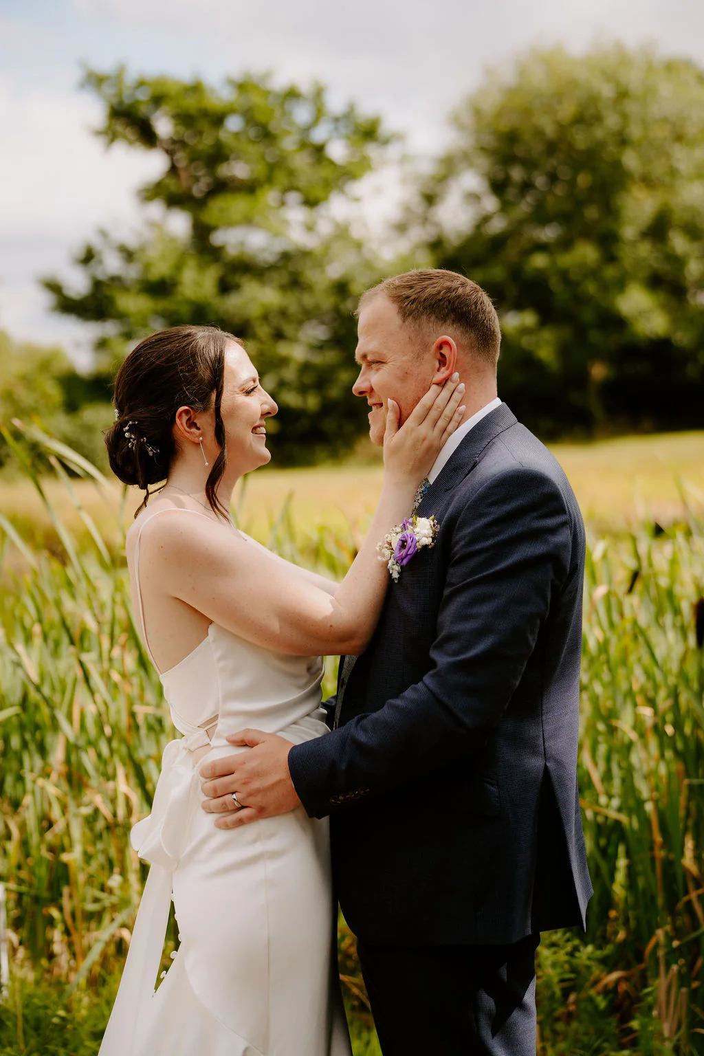 Alison and Kieran smiling together beside tall grasses in the grounds