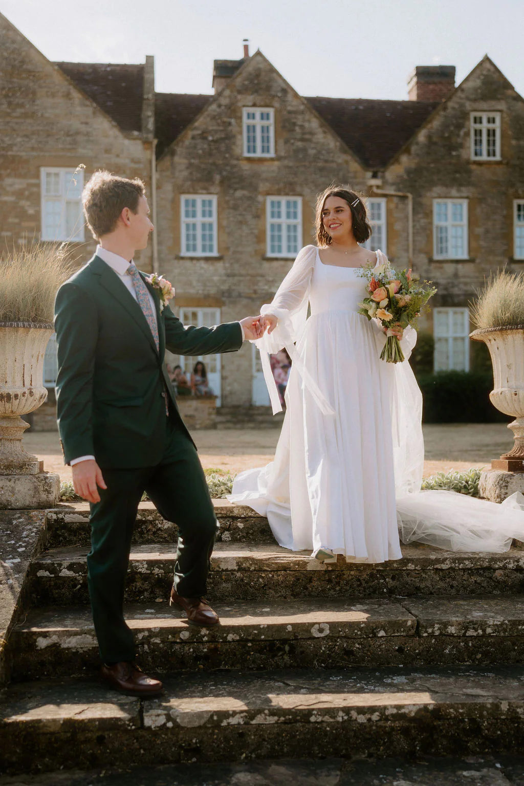 Taylor & Brodie walking hand-in-hand through the private grounds at Talton House in Warwickshire